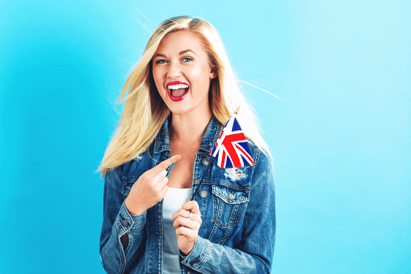 Młoda uśmiechnięta dziewczyna trzymająca flagę Wielkiej Brytanii.