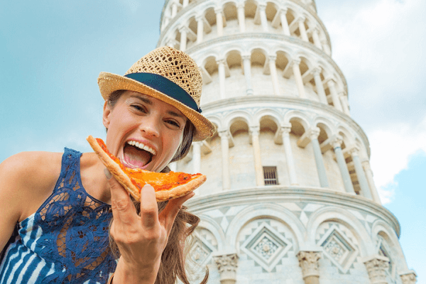 Młoda kobieta z pizza na tle Krzywej Wieży w Pizzie.