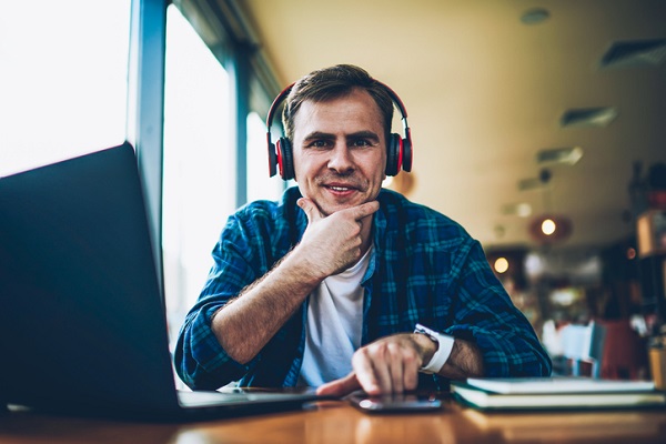 Mężczyzna noszący słuchawki uczą się przed komputerem.