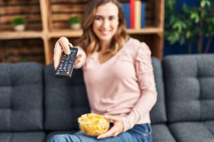Young woman watching tv sitting on sofa at home